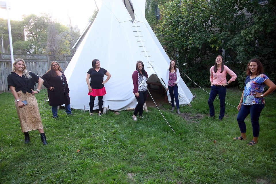 Students standing in front of teepee